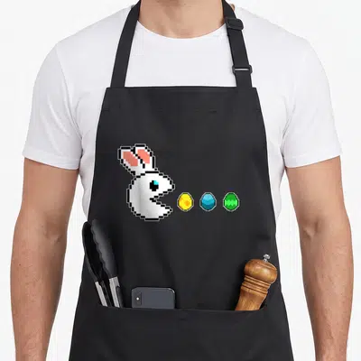 Tablier de cuisine noir avec lapin blanc pixel art type Pac-Man devant trois œufs de Pâques jaunes bleus et verts.