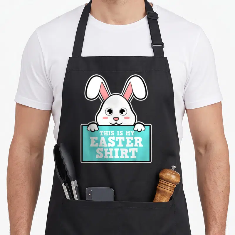 Tablier de cuisine noir avec un lapin blanc tenant une pancarte turquoise portant une inscription humoristique en anglais.
