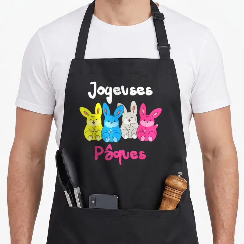 Tablier de cuisine noir avec quatre lapins jaunes, bleus, gris et roses et le texte Joyeuses Pâques imprimé au centre.
