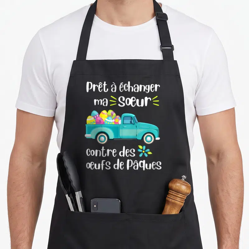 Tablier de cuisine noir avec camion turquoise chargé d'œufs colorés et texte humoristique sur l'échange familial.