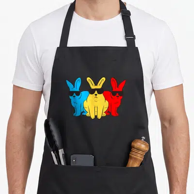 Tablier de cuisine noir avec trois lapins colorés portant des lunettes noires de soleil.
