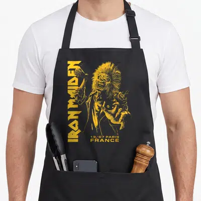 Tablier de cuisine noir avec illustration jaune d'Eddie tenant une hache et le texte Iron Maiden vertical.