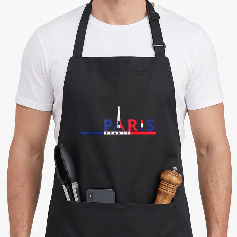 Tablier de cuisine noir avec le mot Paris stylisé par la Tour Eiffel et une bannière tricolore France en dessous.