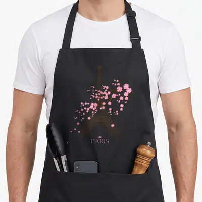 Tablier de cuisine noir avec une illustration de la Tour Eiffel entrelacée de fleurs Sakura roses et le mot Paris en bas.