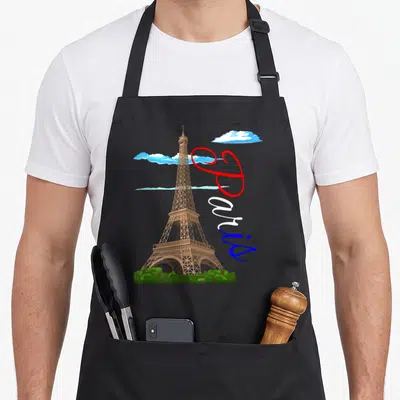 Tablier de cuisine noir avec illustration de la Tour Eiffel, texte Paris tricolore et nuages bleus stylisés.