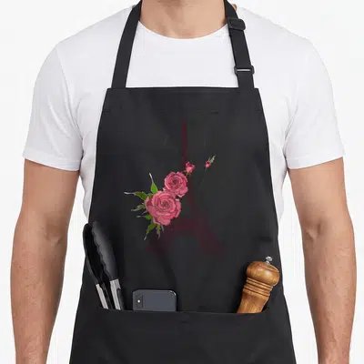 Tablier de cuisine noir avec une illustration de la Tour Eiffel rose et des fleurs de roses aux pétales détaillés.