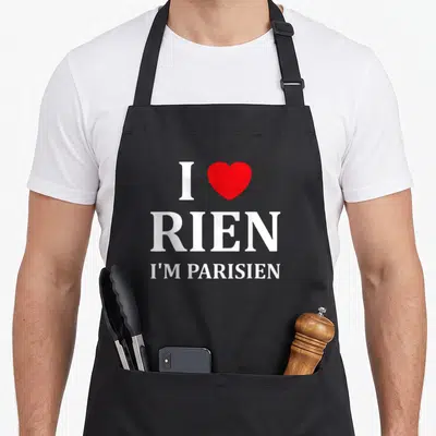 Tablier de cuisine noir avec le texte I love rien i'm parisien et un cœur rouge au centre du design imprimé.