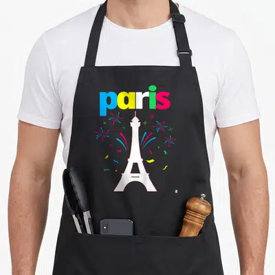 Tablier de cuisine noir avec le mot paris multicolore, une tour Eiffel blanche et des confettis discrets sur fond uni.