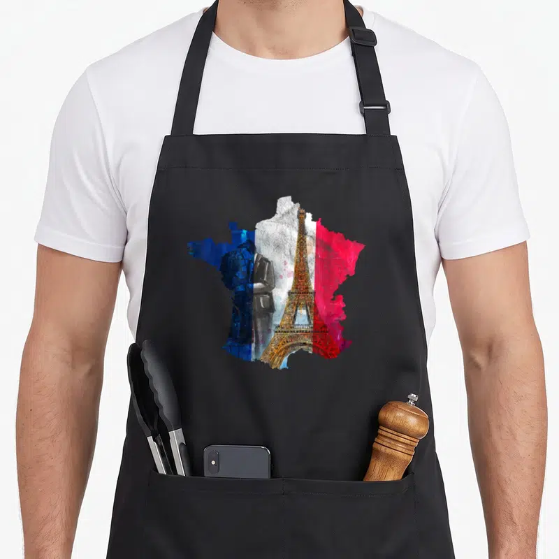 Tablier de cuisine noir avec une carte de France stylisée en bleu blanc rouge, la Tour Eiffel et un portrait masculin.