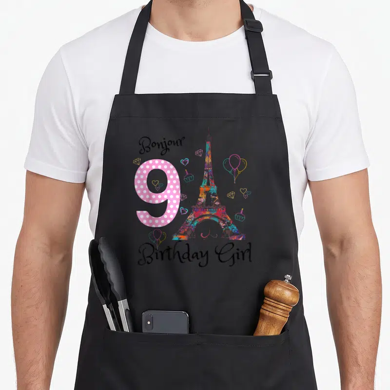 Tablier de cuisine noir avec un grand 9 rose, une Tour Eiffel multicolore et des illustrations festives.
