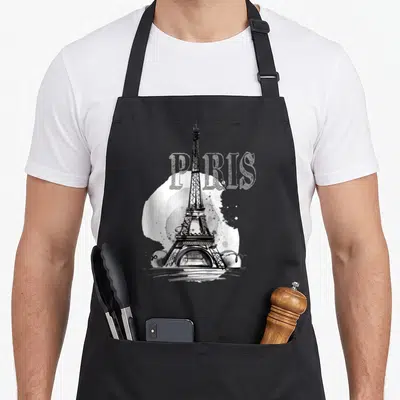 Tablier de cuisine noir avec illustration vintage de la Tour Eiffel et le mot PARIS en arrière-plan.