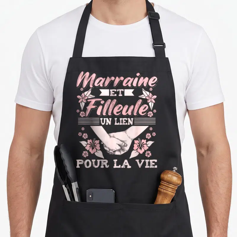 Tablier de cuisine noir avec inscription Marraine et Filleule Un Lien Pour La Vie et illustration de mains jointes entourées de fleurs roses.