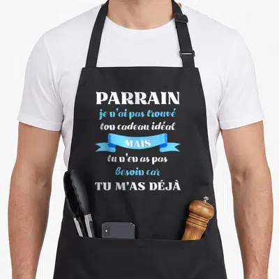 Tablier de cuisine noir avec inscription blanche et bleue « Parrain tu m'as déjà » sur fond uni.