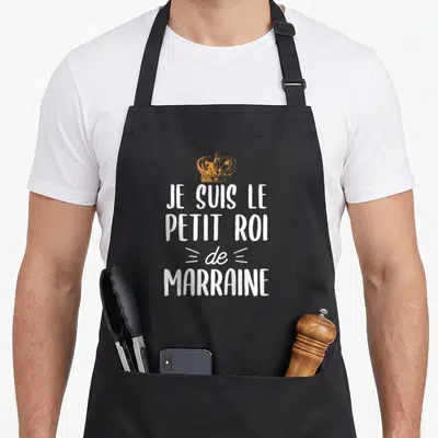 Tablier de cuisine noir avec inscription blanche Je suis le petit roi de marraine surmonté d'une couronne dorée stylisée.