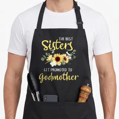 Tablier de cuisine noir avec des tournesols jaunes et le texte Les meilleures sœurs sont promues au rang de marraine nouvelle marraine.