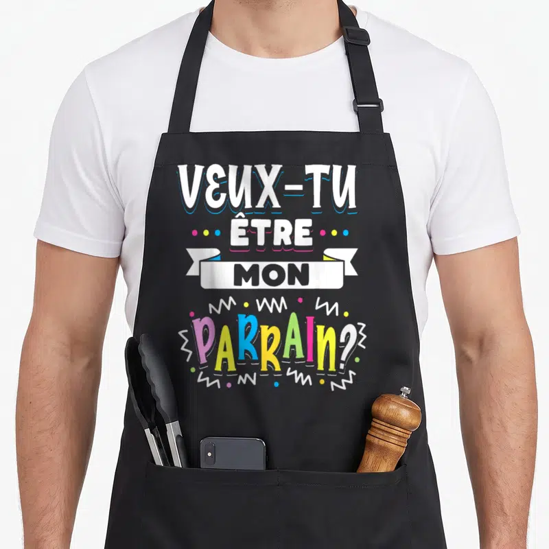 Tablier de cuisine noir avec inscription Veux Tu Etre Mon Parrain en lettres multicolores et décorations graphiques.