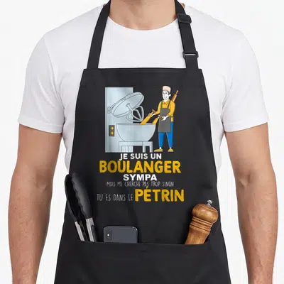 Tablier de cuisine noir avec illustration d'un boulanger et du texte Je suis un boulanger sympa mais me cherche pas trop sinon tu es dans le pétrin.