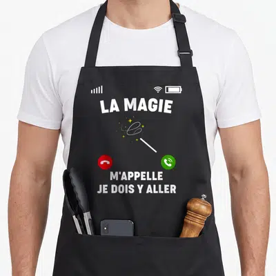 Tablier de cuisine noir avec interface téléphone affichant La Magie M'Appelle et une baguette magique jaune.