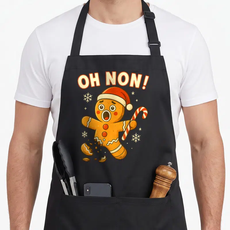 Tablier de cuisine noir avec bonhomme pain d'épices en panique tenant une canne à sucre et le texte Oh Non au-dessus.