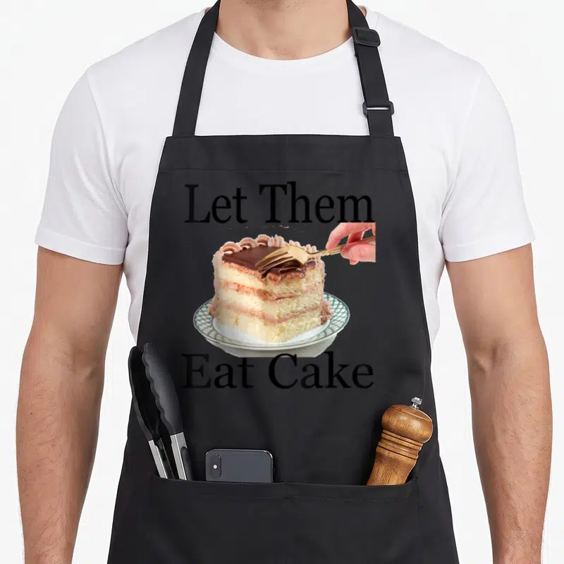 Tablier de cuisine noir avec Laissez-les manger du gâteau et une main tenant une fourche sur un gâteau au chocolat.