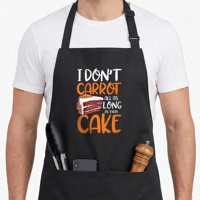 Tablier de cuisine noir avec une illustration de gâteau carotte et un texte humoristique en anglais.