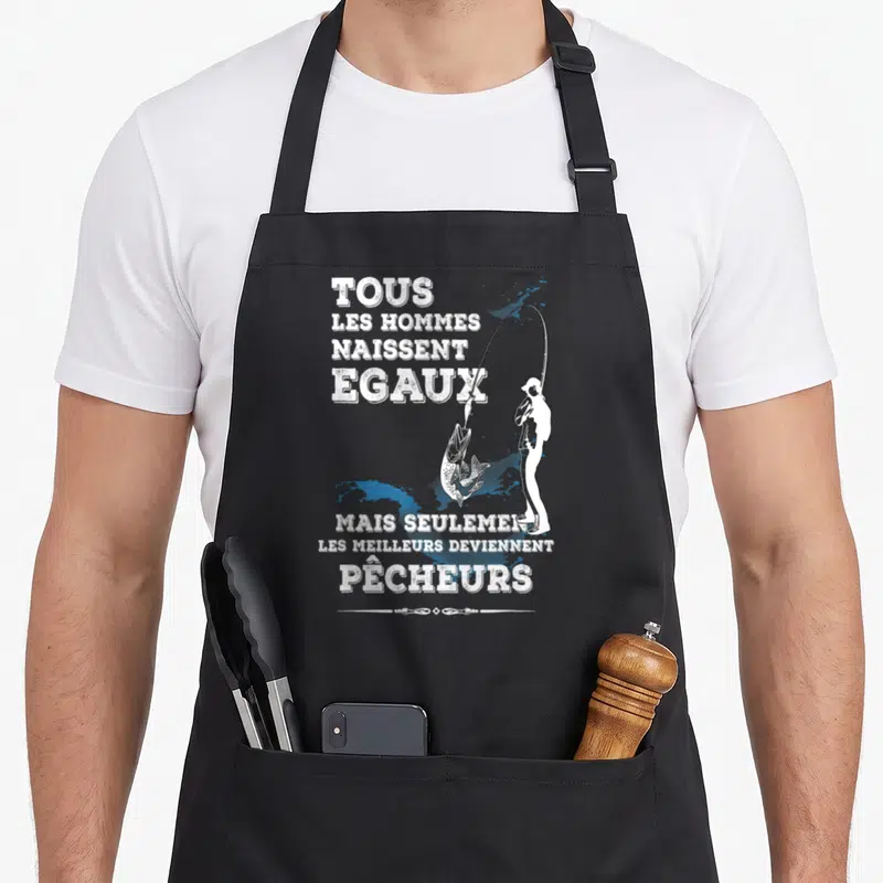 Tablier de cuisine noir avec une silhouette blanche pêchant un saumon et le texte Tous les hommes naissent égaux mais seulement les meilleurs deviennent pêcheurs.