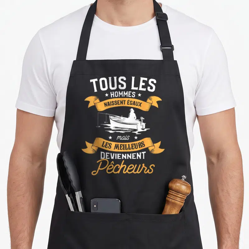 Tablier de cuisine noir avec inscription tous les hommes naissent égaux mais les meilleurs deviennent pêcheurs et silhouette de bateau.