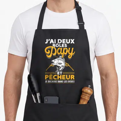 Tablier de cuisine noir avec illustration de brochet et texte J'ai deux rôles Papy et Pêcheur en blanc et orange.