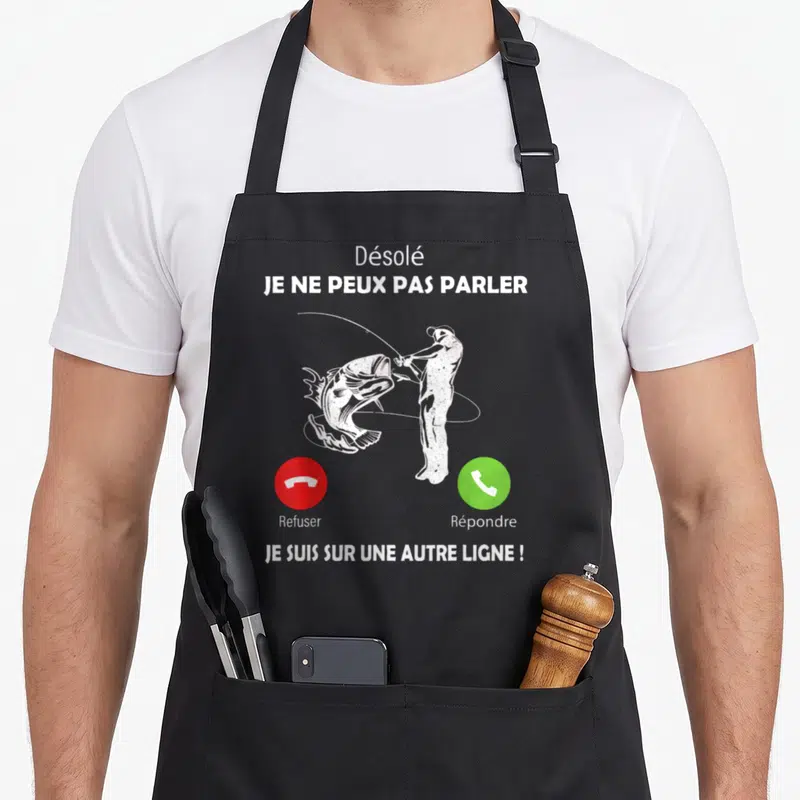 Tablier de cuisine noir avec inscription blanche et silhouette d'un pêcheur tenant une canne face à un gros poisson sautant.