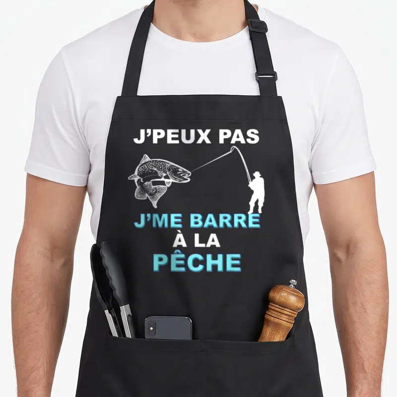 Tablier de cuisine noir avec une silhouette de pêcheur blanchâtre tirant un gros poisson et le texte Je peux pas je me barre à la pêche en blanc et bleu.