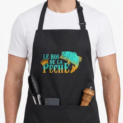 Tablier de cuisine noir avec illustration d'un poisson sautant turquoise et orange et le texte Le Roi de la Pêche.