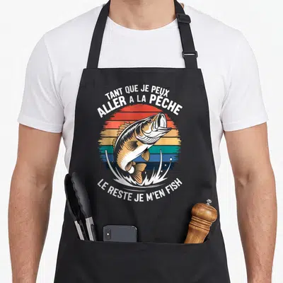 Tablier de cuisine noir avec illustration d'un poisson bondissant et texte blanc sur fond de soleil coloré.