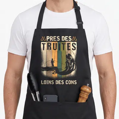 Tablier de cuisine noir avec inscription Pres des truites loin des cons et silhouette de pêcheur en barque.