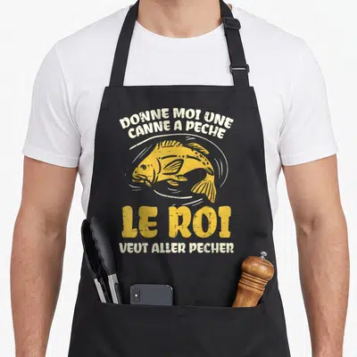 Tablier de cuisine noir avec illustration d'un poisson jaune et texte blanc donne moi une canne a peche le roi veut aller pecher