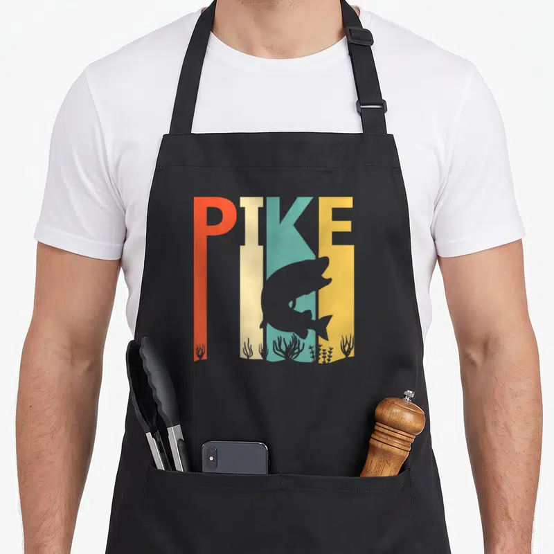 Tablier de cuisine noir avec l'inscription PIKE en couleurs et silhouette de poisson gris au centre du motif imprimé.
