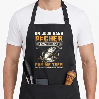 Tablier de cuisine noir avec illustration d'un saumon et texte humoristique sur la pêche en blanc et orange.