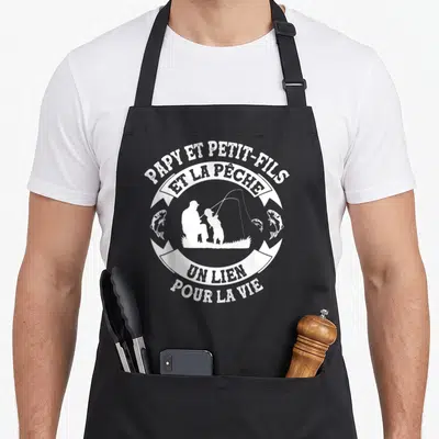 Tablier de cuisine noir avec un motif circulaire blanc représentant un grand-père et un enfant en silhouette au bord de l'eau.
