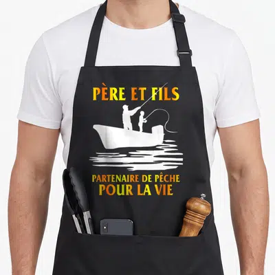 Tablier de cuisine noir avec silhouette blanche d'un père et fils dans un bateau et texte orange Père et fils partenaire de pêche pour la vie.