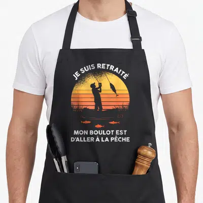 Tablier de cuisine noir avec silhouette pêcheur et texte Je suis retraité mon boulot est d'aller à la pêche sur fond orange.