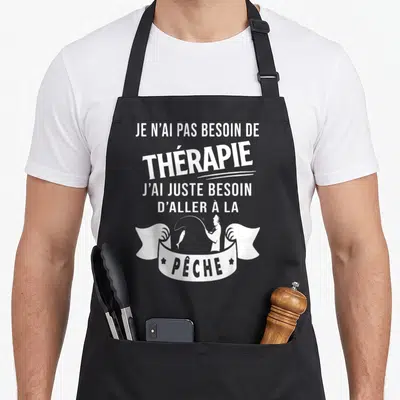 Tablier de cuisine noir avec inscription blanche et silhouette d'un pêcheur tenant une canne au-dessus d'un poisson dans un ruban.