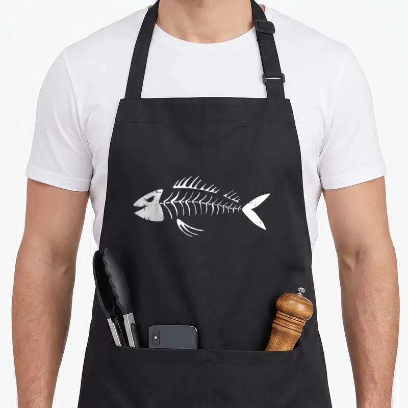 Tablier de cuisine noir avec illustration d'une arête de poisson squelette blanche stylisée au centre.