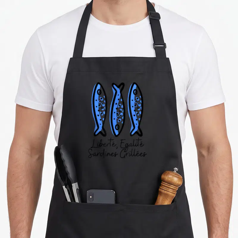 Tablier de cuisine noir avec trois sardines bleues stylisées et texte Liberté Égalité Sardines Grillées en bas.