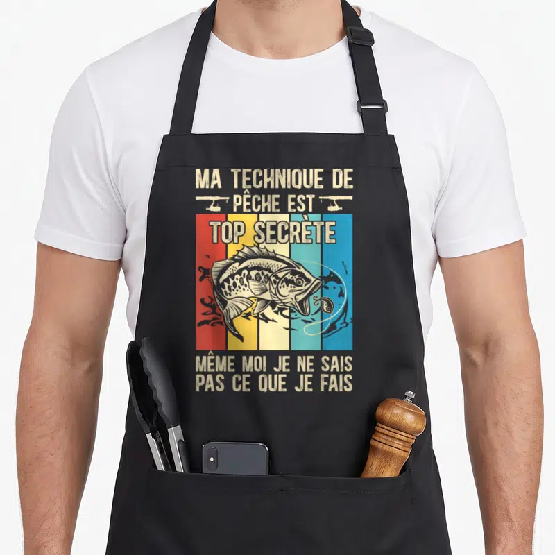Tablier de cuisine noir avec illustration rétro d'un poisson et texte humoristique sur la pêche.