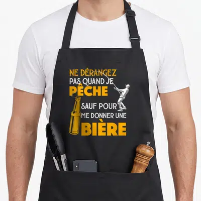 Tablier de cuisine noir avec silhouette pêcheur et texte Ne dérangez pas quand je pêche bière en orange et blanc.