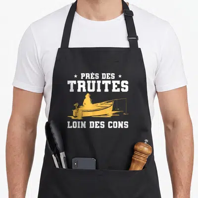 Tablier de cuisine noir avec silhouette pêcheur en barque jaune et texte blanc Près de truites loin des cons