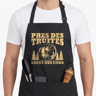 Tablier de cuisine noir avec inscription Pres des truites loins des cons et illustration d'un pêcheur.