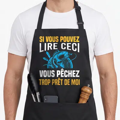 Tablier de cuisine noir avec illustration bleue d'un poisson et texte blanc et orange Sur le devant du vêtement.