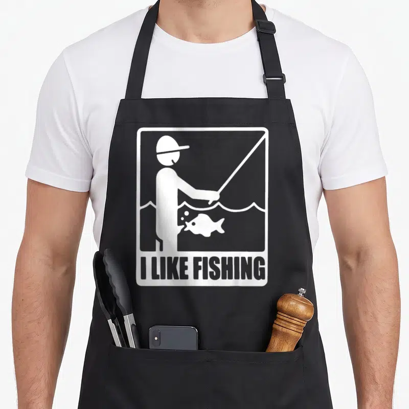 Tablier de cuisine noir avec une illustration blanche d'un pêcheur et du texte I LIKE FISHING en bas.
