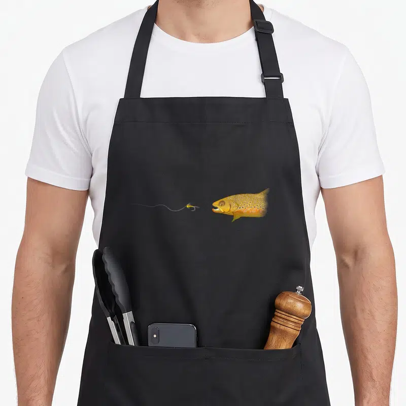 Tablier de cuisine noir avec une illustration de truite brune et d'une mouche artificielle sur fil.