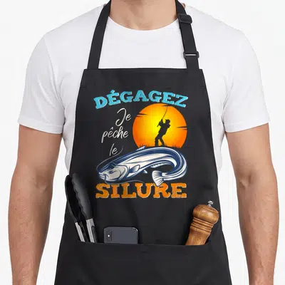 Tablier de cuisine noir avec illustration d'un silure et d'un pêcheur devant un soleil orange